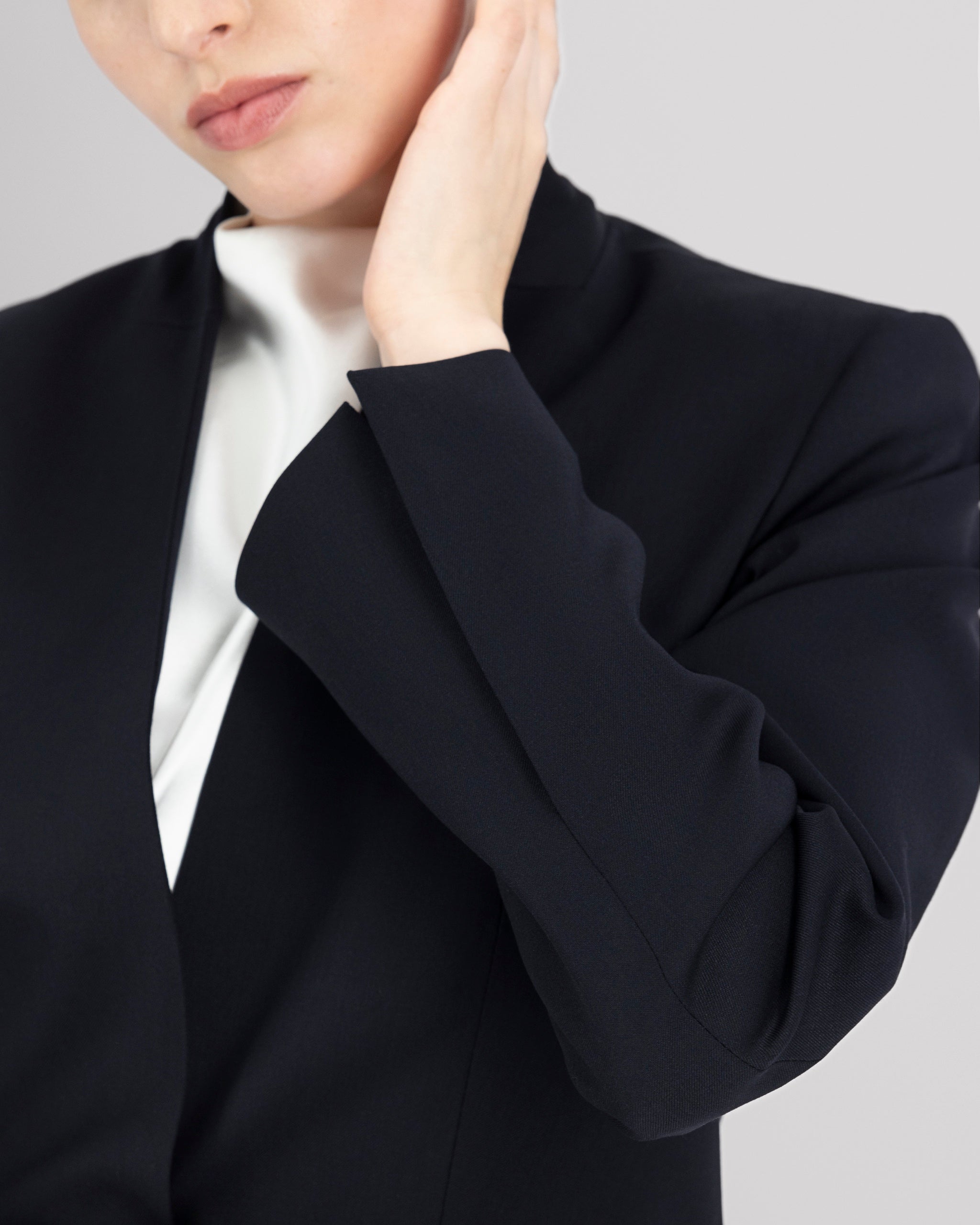 Blazer mit nach vorne versetzter Seitennaht und formgebenden Passformnähten für eine schlanke, konturierte Silhouette. Schulterpolster verleihen klare Struktur, zweiteilige Ärmel sorgen für präzisen Sitz. Dezente Details wie Ärmelschlitz, Corozo-Knopf, Rückenschlitz und schmale Pattentasche unterstreichen das reduzierte, fliessende Design.