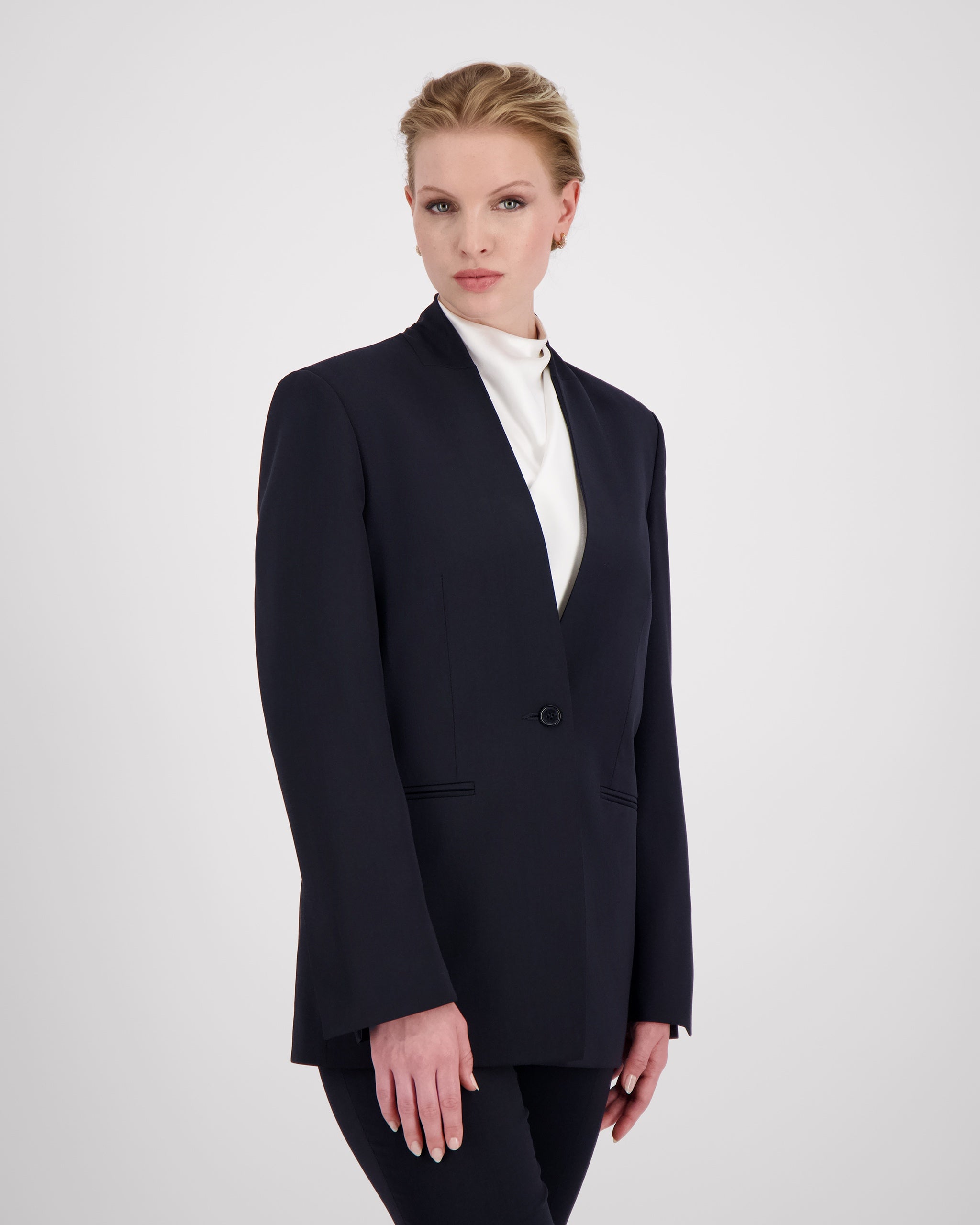 Blazer mit nach vorne versetzter Seitennaht und formgebenden Passformnähten für eine schlanke, konturierte Silhouette. Schulterpolster verleihen klare Struktur, zweiteilige Ärmel sorgen für präzisen Sitz. Dezente Details wie Ärmelschlitz, Corozo-Knopf, Rückenschlitz und schmale Pattentasche unterstreichen das reduzierte, fliessende Design.