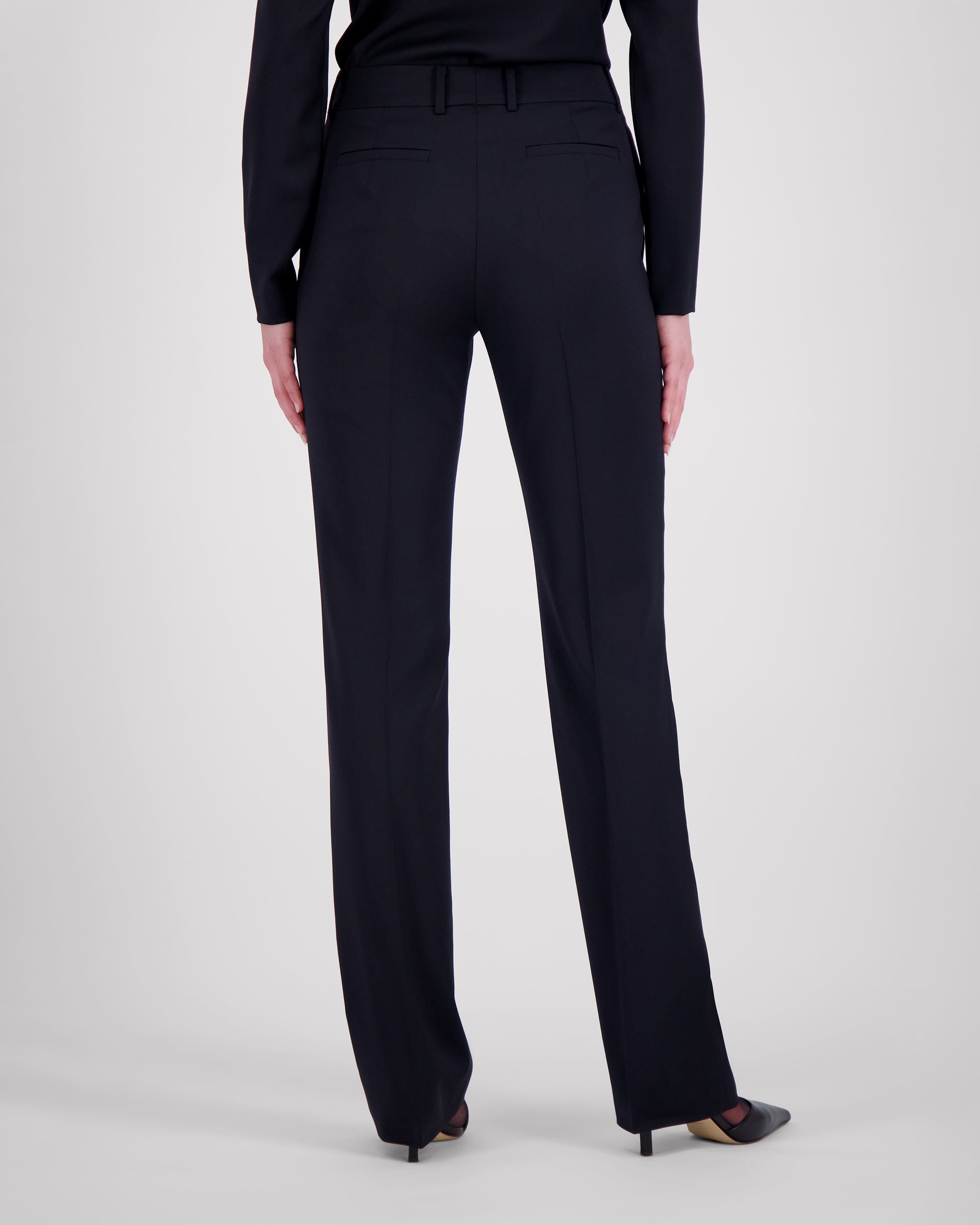Hose aus navyfarbener Merinowolle mit fliessender, schmaler Silhouette. Charakteristische Mittelnaht vorn und feine Bügelfalte hinten unterstreichen die klare Linienführung. Verdeckter Bundverschluss mit Corozo-Knopf sorgt für eine glatte Front. Seitliche Eingrifftaschen, rückwärtige Pattentaschen und sanfte Abnäher formen eine feminine Passform.