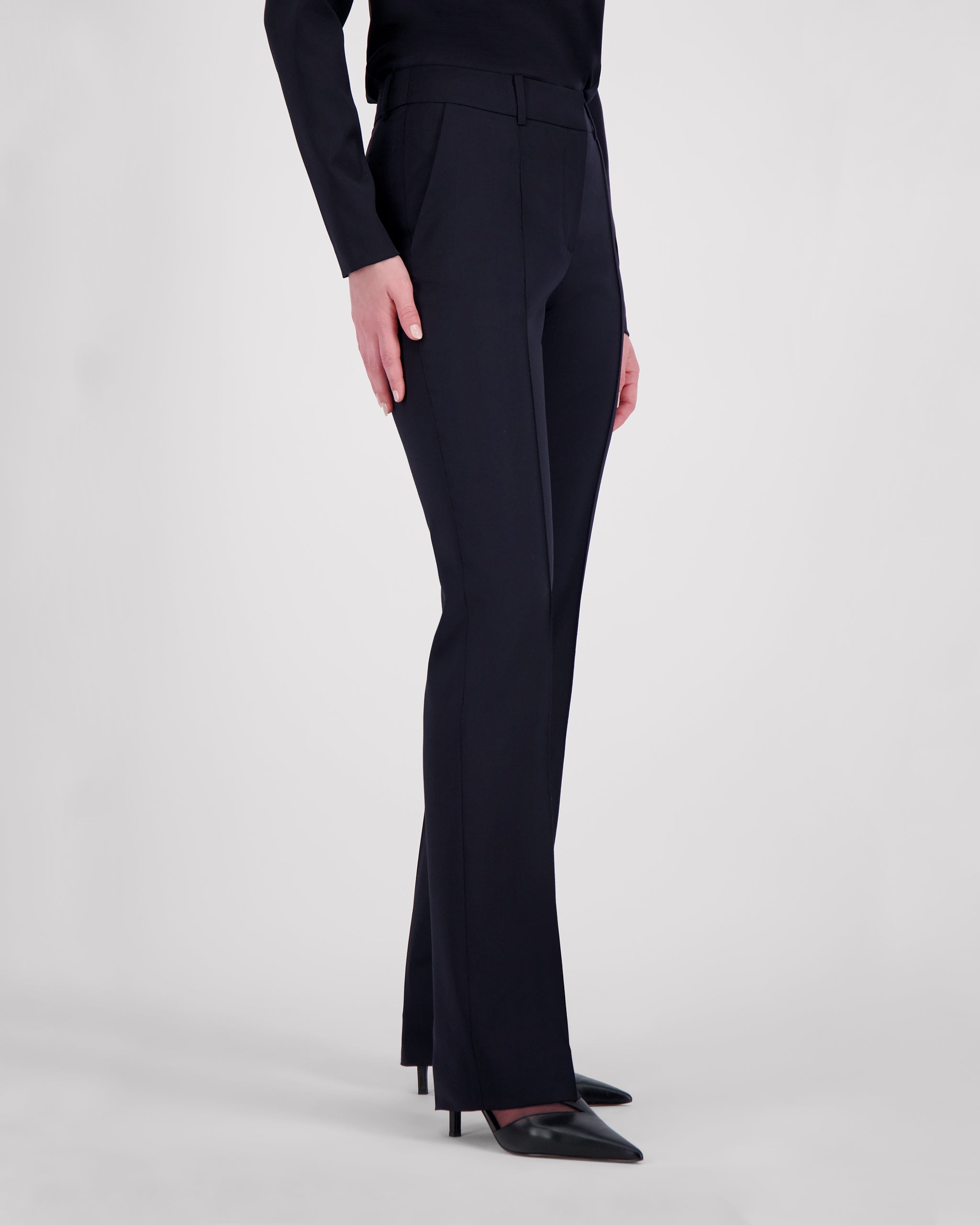 Hose aus navyfarbener Merinowolle mit fliessender, schmaler Silhouette. Charakteristische Mittelnaht vorn und feine Bügelfalte hinten unterstreichen die klare Linienführung. Verdeckter Bundverschluss mit Corozo-Knopf sorgt für eine glatte Front. Seitliche Eingrifftaschen, rückwärtige Pattentaschen und sanfte Abnäher formen eine feminine Passform.