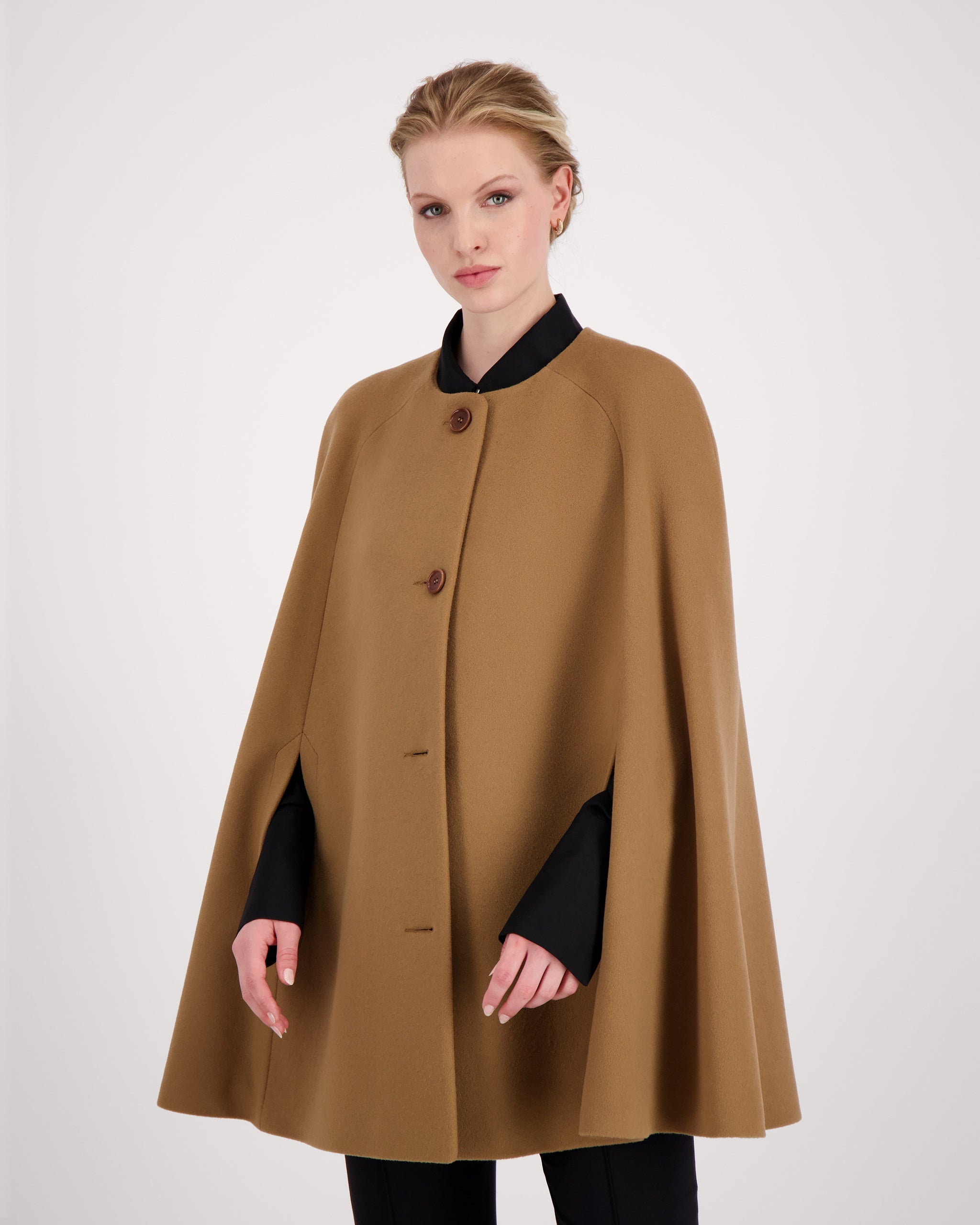 Cape-Mantel aus reinem Kaschmir mit sanft modellierenden Schulterabnähern und fein gearbeiteten Ärmelschlitzen mit zarter Absteppung. Der matte Vier-Knopf-Verschluss aus Corozo hält die Silhouette klar und puristisch. Dezente Eingriffschlitze und eine versteckte Innentasche verbinden Funktionalität mit eleganter, reduzierter Formensprache.