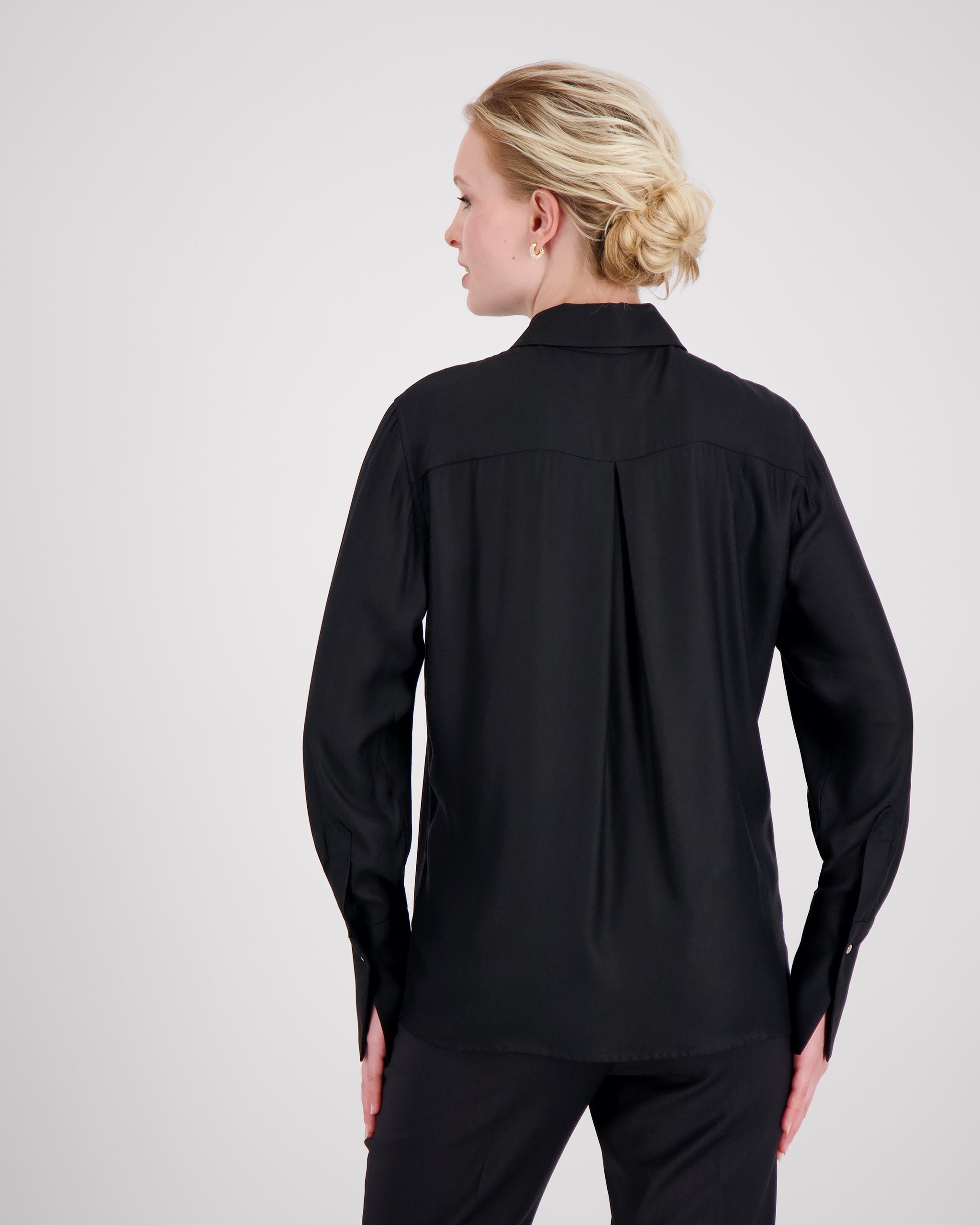 Elegante Bluse mit leicht vergrössertem Kragen und feiner Kantensteppung für ein markantes, selbstbewusstes Statement. Locker fallende Silhouette mit nach vorne versetzter Schulternaht und Rückenfalte für strukturierten, fliessenden Sitz. Durchgehende Knopfleiste mit Corozo-Knöpfen und extralangen Manschetten für präzise, detailreiche Verarbeitung.