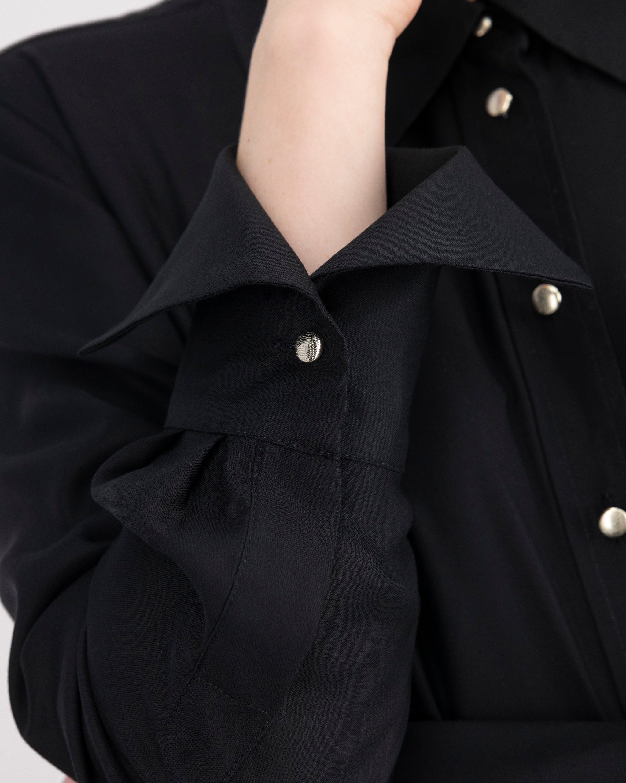 Elegante Bluse mit leicht vergrössertem Kragen und feiner Kantensteppung für ein markantes, selbstbewusstes Statement. Locker fallende Silhouette mit nach vorne versetzter Schulternaht und Rückenfalte für strukturierten, fliessenden Sitz. Durchgehende Knopfleiste mit Corozo-Knöpfen und extralangen Manschetten für präzise, detailreiche Verarbeitung.