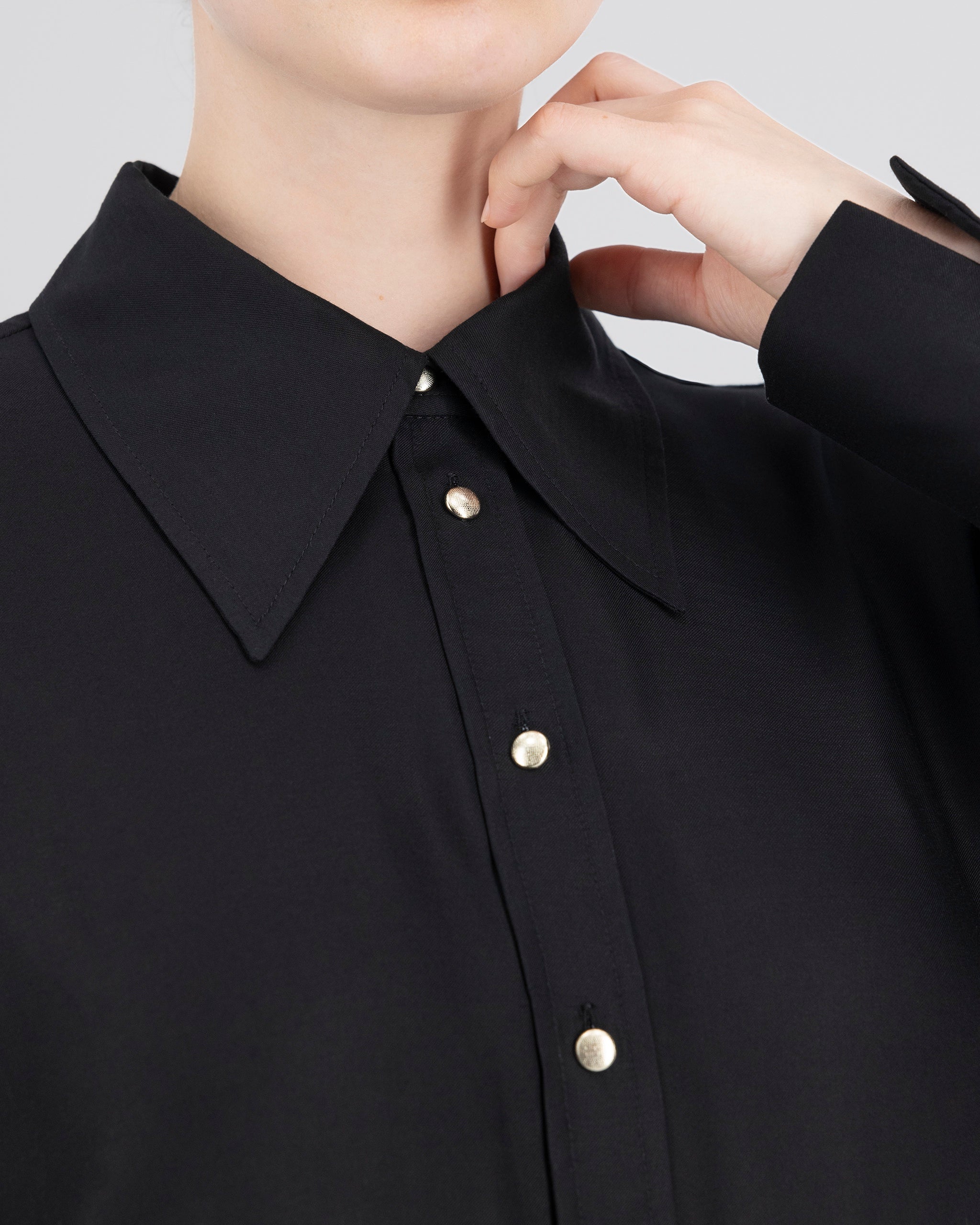 Elegante Bluse mit leicht vergrössertem Kragen und feiner Kantensteppung für ein markantes, selbstbewusstes Statement. Locker fallende Silhouette mit nach vorne versetzter Schulternaht und Rückenfalte für strukturierten, fliessenden Sitz. Durchgehende Knopfleiste mit Corozo-Knöpfen und extralangen Manschetten für präzise, detailreiche Verarbeitung.