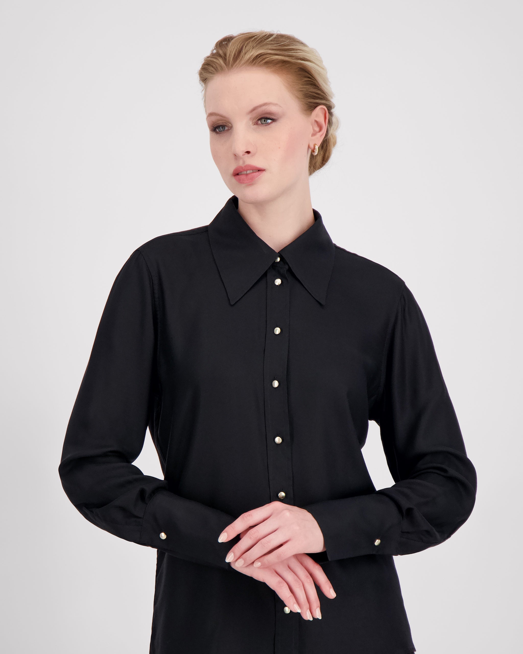 Elegante Bluse mit leicht vergrössertem Kragen und feiner Kantensteppung für ein markantes, selbstbewusstes Statement. Locker fallende Silhouette mit nach vorne versetzter Schulternaht und Rückenfalte für strukturierten, fliessenden Sitz. Durchgehende Knopfleiste mit Corozo-Knöpfen und extralangen Manschetten für präzise, detailreiche Verarbeitung.