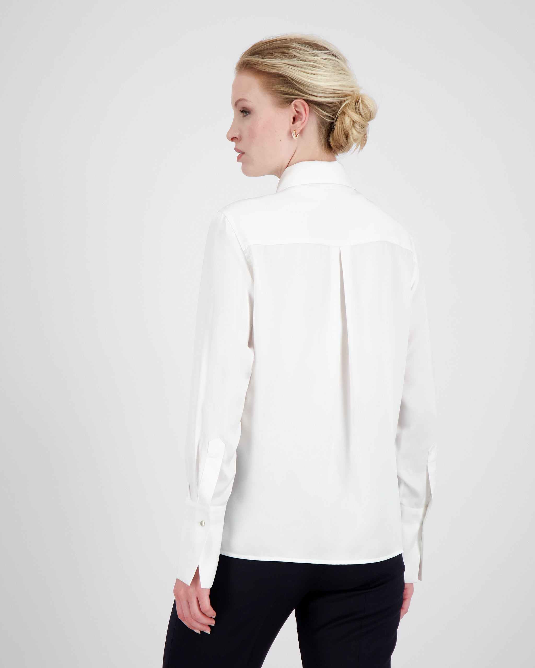 Bluse aus Peace Silk mit modernem, leicht vergrössertem Kragen und feiner Kantensteppung für einen ausdrucksstarken Look. Nach vorne versetzte Schulternähte, Rückenfalte und locker fallende Silhouette sorgen für entspannte Eleganz. Goldene Metallknöpfe, extralange Manschetten und ein fein abgesteppt Saum unterstreichen die präzise Verarbeitung.