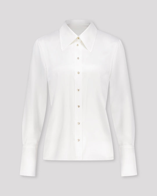 Bluse aus Peace Silk mit modernem, leicht vergrössertem Kragen und feiner Kantensteppung für einen ausdrucksstarken Look. Nach vorne versetzte Schulternähte, Rückenfalte und locker fallende Silhouette sorgen für entspannte Eleganz. Goldene Metallknöpfe, extralange Manschetten und ein fein abgesteppt Saum unterstreichen die präzise Verarbeitung.