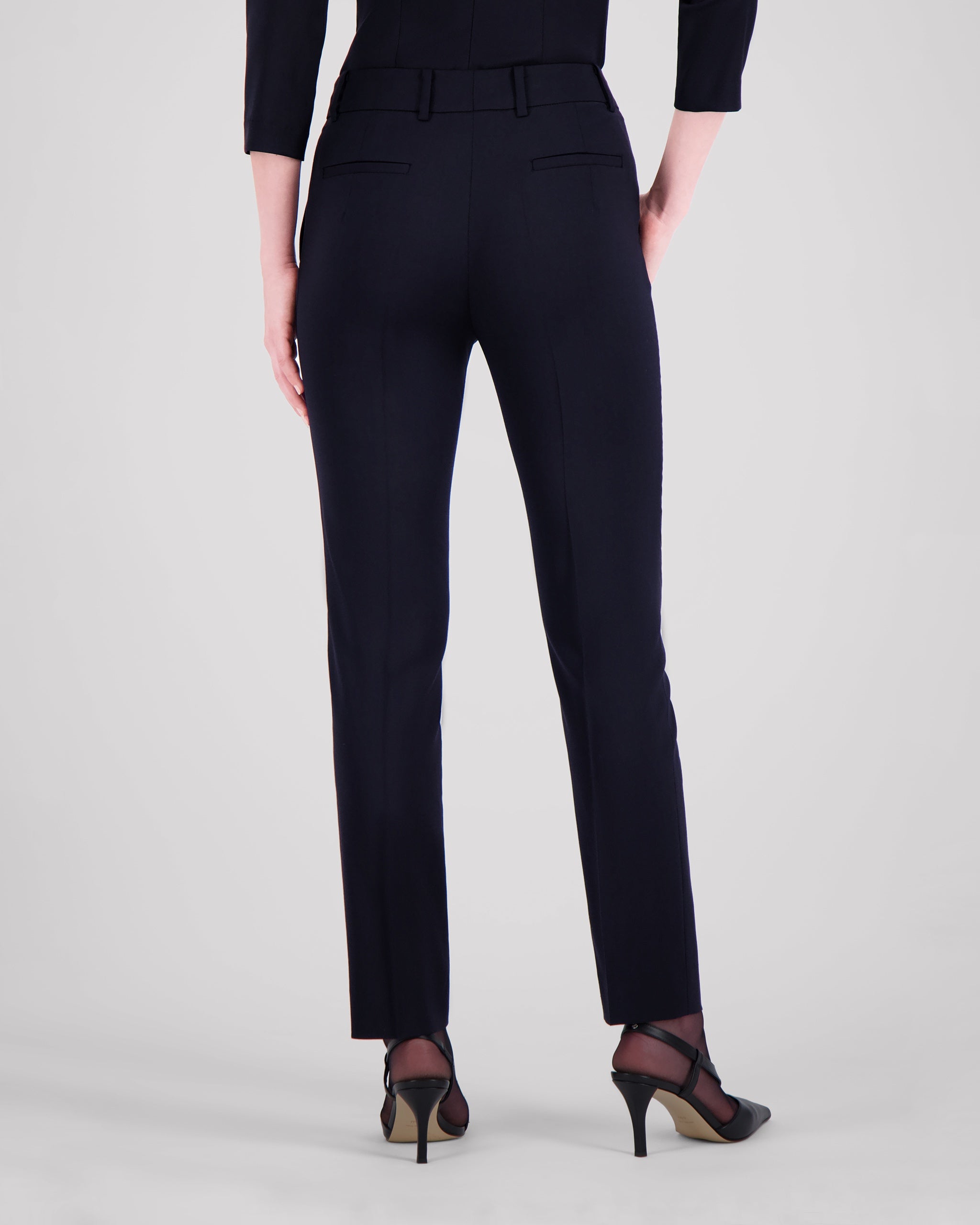 Knöchellange Hose mit schmalem Beinverlauf und klarer, reduzierter Silhouette. Feine Mittelnaht vorn und Bügelfalte hinten betonen die Linie dezent. Seitliche Eingrifftaschen, rückwärtige Pattentaschen und sanfte Abnäher formen eine feminine Kontur. Verdeckter Bundverschluss mit Corozo-Knopf und schwarze Baumwollknöpfe runden das puristische Design ab.