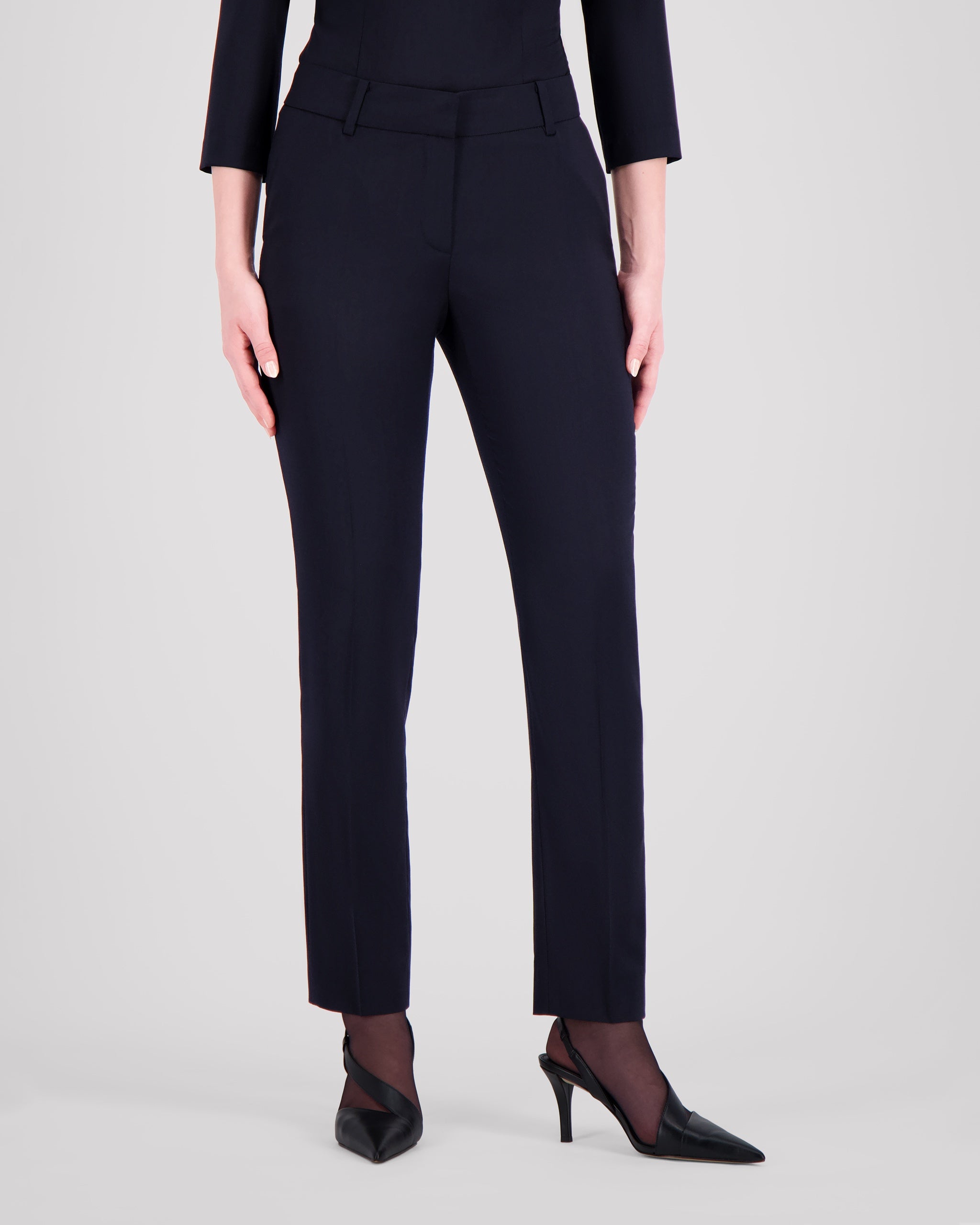 Knöchellange Hose mit schmalem Beinverlauf und klarer, reduzierter Silhouette. Feine Mittelnaht vorn und Bügelfalte hinten betonen die Linie dezent. Seitliche Eingrifftaschen, rückwärtige Pattentaschen und sanfte Abnäher formen eine feminine Kontur. Verdeckter Bundverschluss mit Corozo-Knopf und schwarze Baumwollknöpfe runden das puristische Design ab.