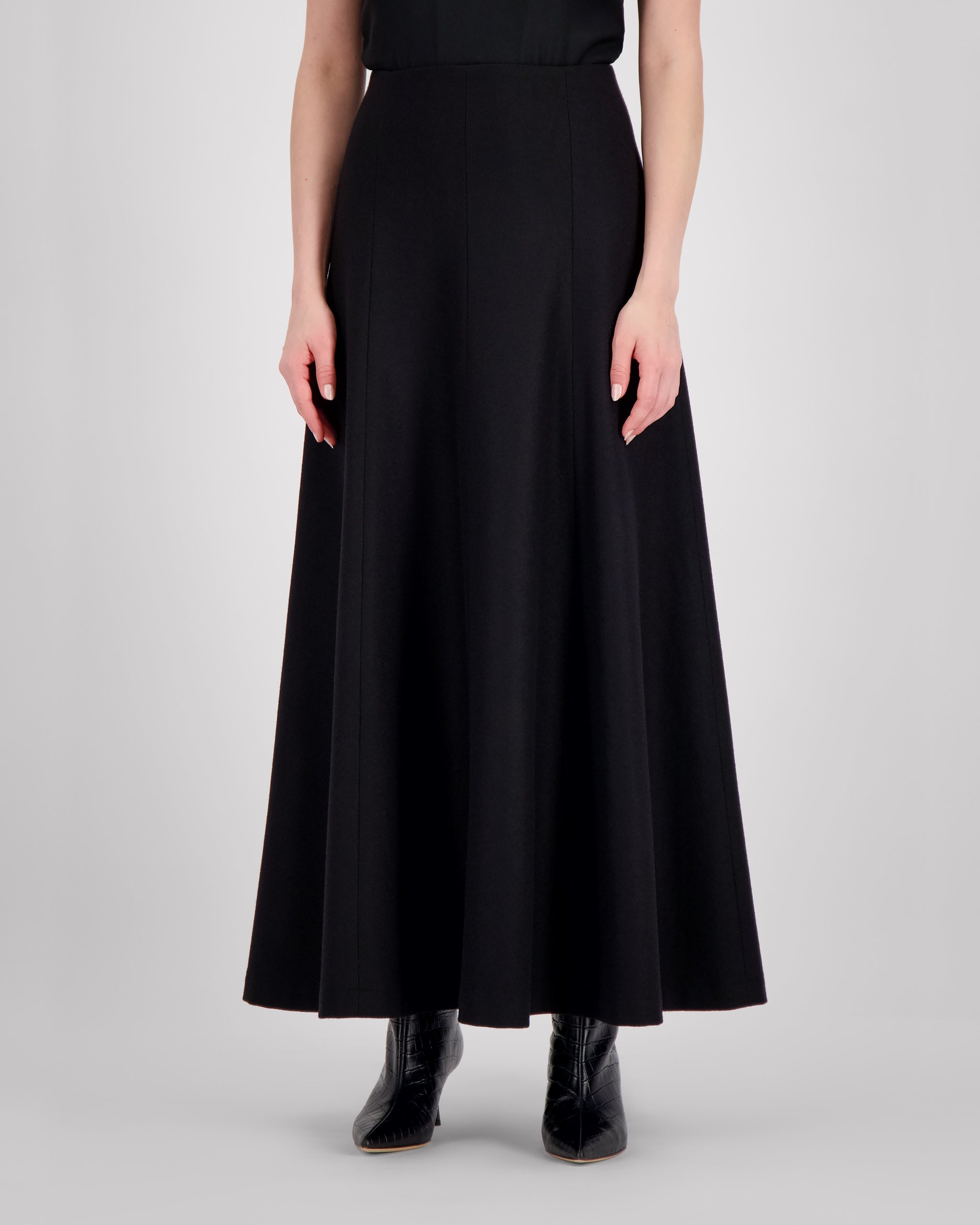 Knöchellanger Rock aus reiner schwarzer Merinowolle mit klarer, weich fallender Silhouette. Ungesteppt gearbeitete Silhouettennähte sorgen für skulpturale Eleganz. Der nahtverdeckte Reissverschluss hinten und der doppelt umgeschlagene, fein abgesteppt Saum vollenden die Form mit technischer Präzision und stabiler Linienführung.