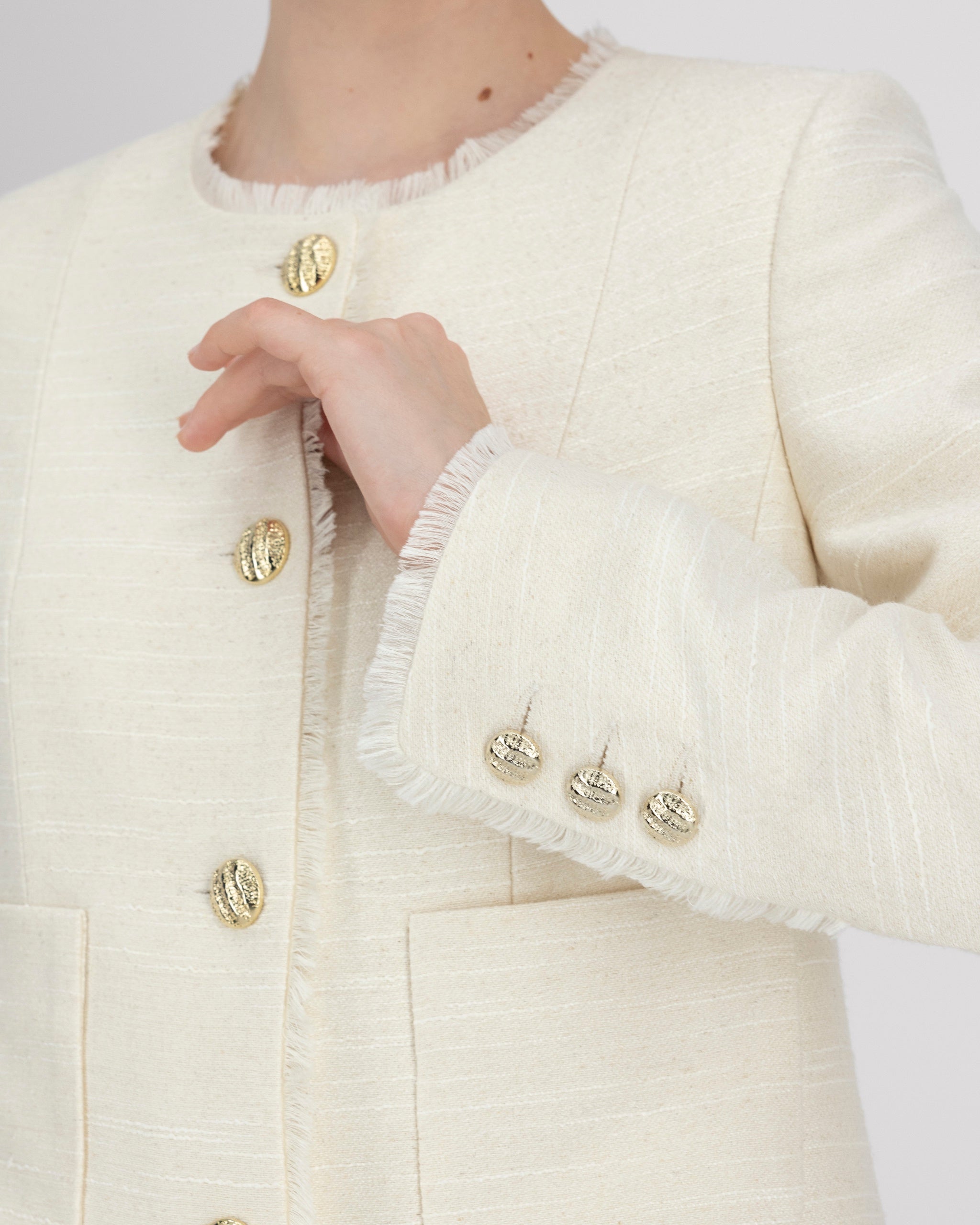 Jackett mit ausgefranstem Halsausschnitt und roher Frontkante für eine subtile, avantgardistische Note. Schulterpolster, Passformnähte und versetzte Seitennaht formen eine elegante Silhouette. Zweiteilige Ärmel, goldene Metallknöpfe und dezente Taschen stehen für präzise Handwerkskunst. Ausgefranster Saum und Ärmelschlitze setzen künstlerische Akzente.