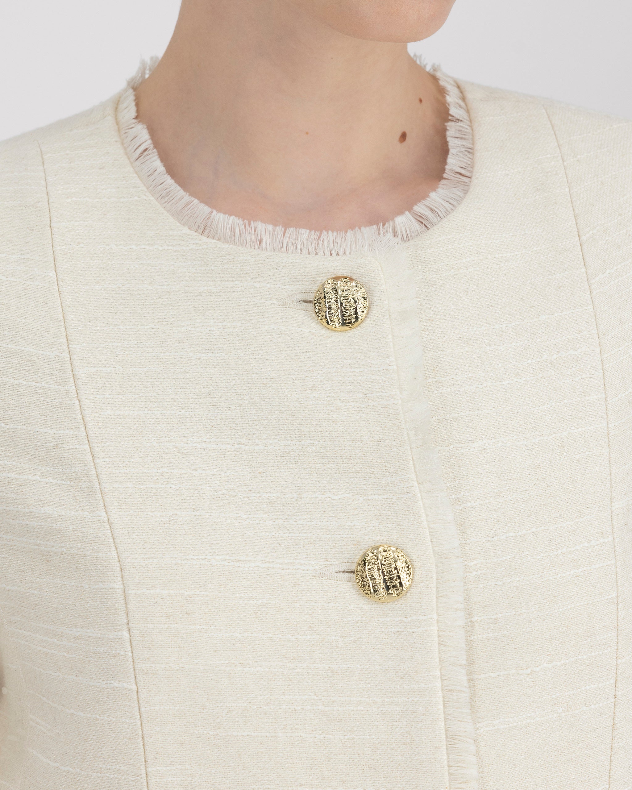 Jackett mit ausgefranstem Halsausschnitt und roher Frontkante für eine subtile, avantgardistische Note. Schulterpolster, Passformnähte und versetzte Seitennaht formen eine elegante Silhouette. Zweiteilige Ärmel, goldene Metallknöpfe und dezente Taschen stehen für präzise Handwerkskunst. Ausgefranster Saum und Ärmelschlitze setzen künstlerische Akzente.