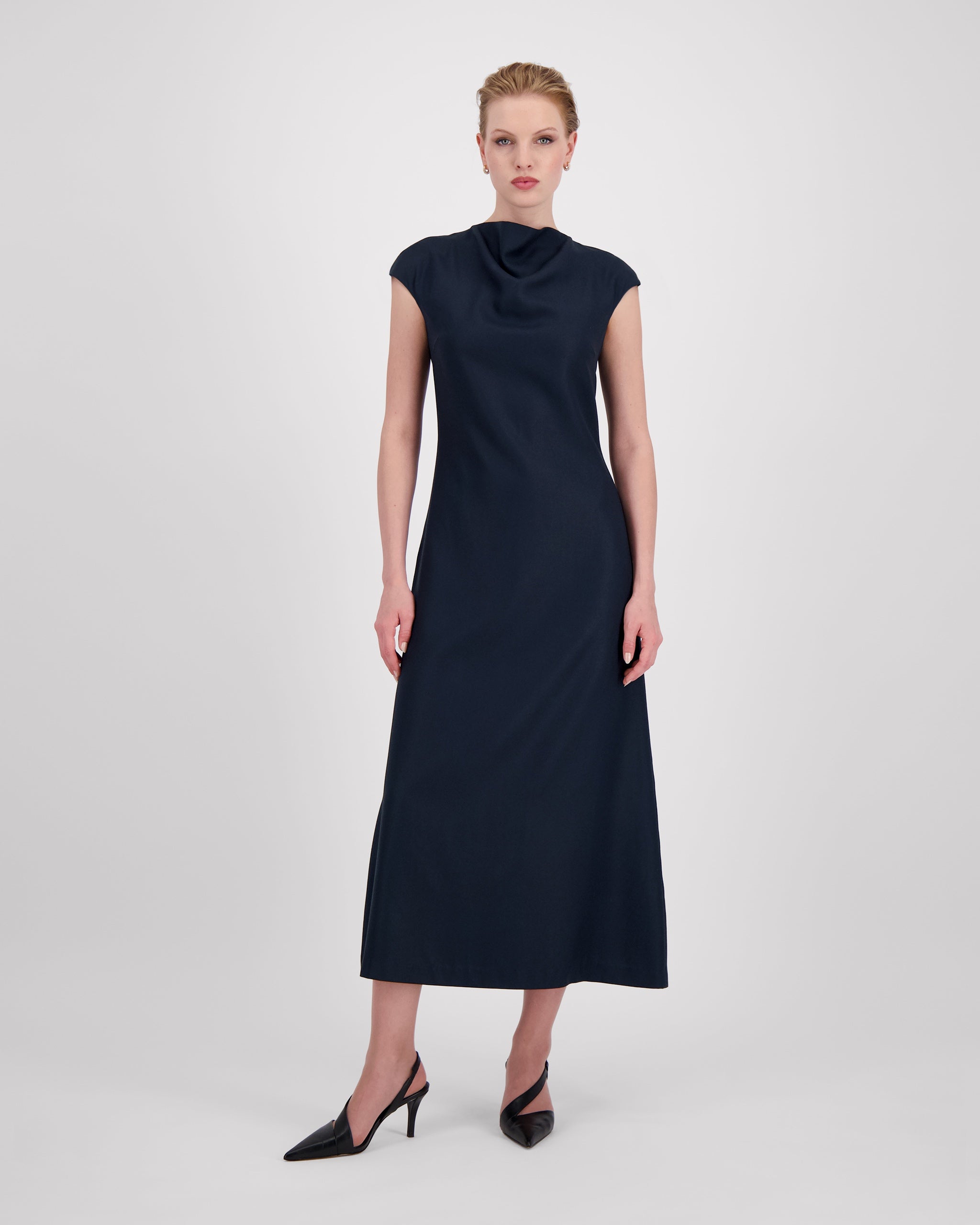 Kleid mit sanft drapiertem Halsausschnitt und nahtloser Verarbeitung für eine klare, elegante Halslinie. Lockere Passform mit formenden Abnähern vorn und weich fallendem, leicht ausgestelltem Rock für anmutige Bewegung. Nahtverdeckter Reissverschluss hinten und unsichtbarer Blindsaum sorgen für ein puristisches, präzise gefertigtes Finish.