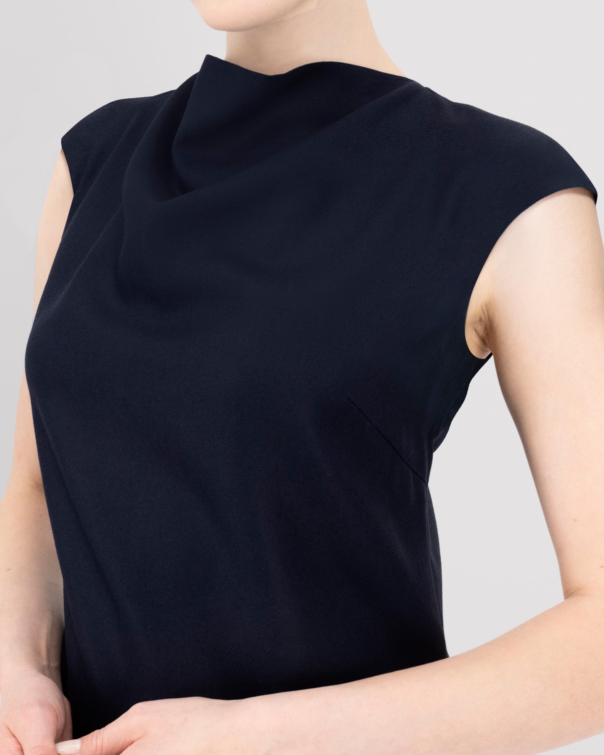 Kleid mit sanft drapiertem Halsausschnitt und nahtloser Verarbeitung für eine klare, elegante Halslinie. Lockere Passform mit formenden Abnähern vorn und weich fallendem, leicht ausgestelltem Rock für anmutige Bewegung. Nahtverdeckter Reissverschluss hinten und unsichtbarer Blindsaum sorgen für ein puristisches, präzise gefertigtes Finish.