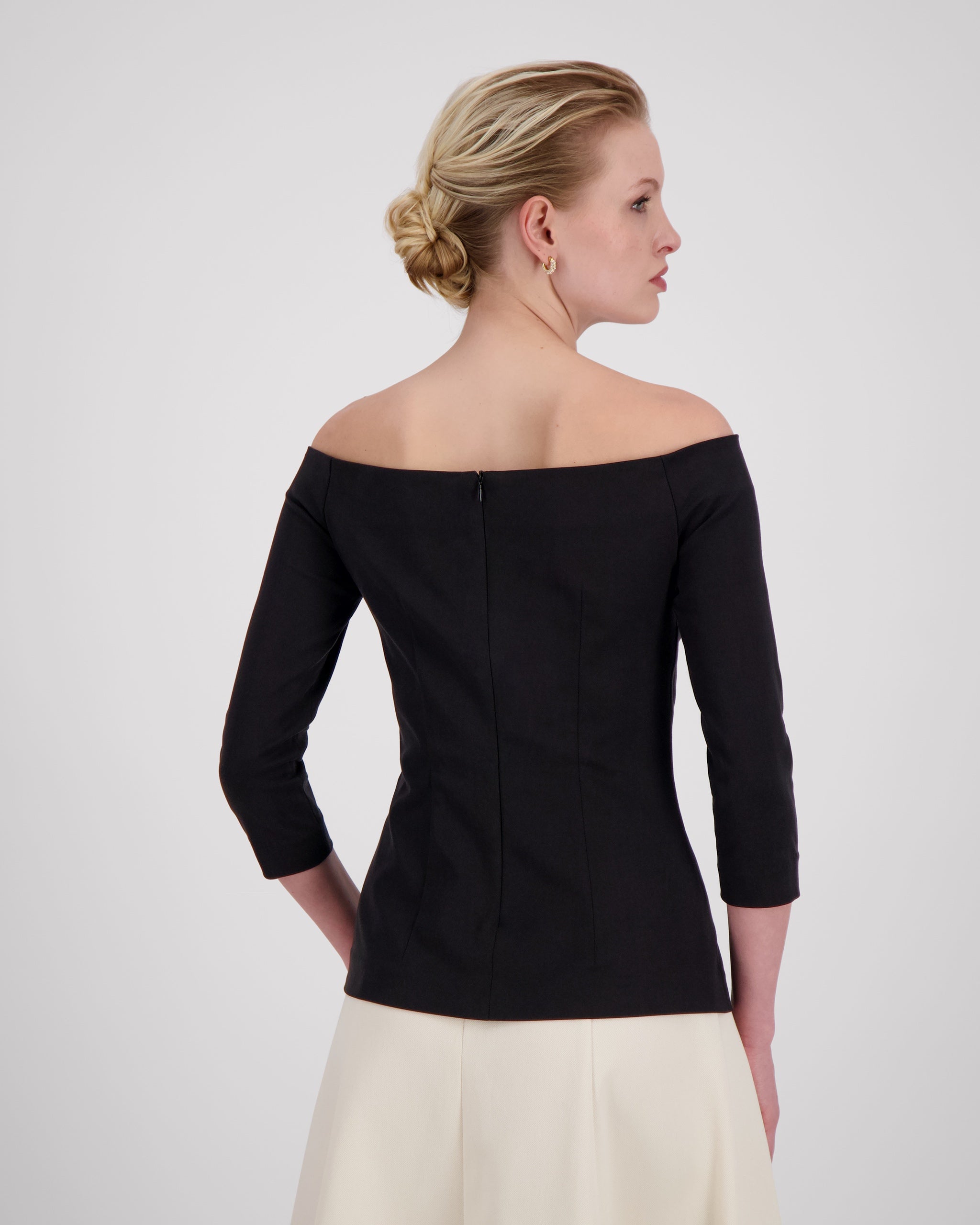 Top mit geradem Ausschnitt vorne und hinten, 3/4-Ärmeln und feinen Abnähern für eine strukturierte, feminine Silhouette. Der nahtverdeckte Reissverschluss im Rücken und der gerade Saum mit Blindsäumen unterstreichen die klare Linienführung. Fliessende Materialien und präzise Verarbeitung verleihen dem Design schlichte Eleganz und Leichtigkeit.