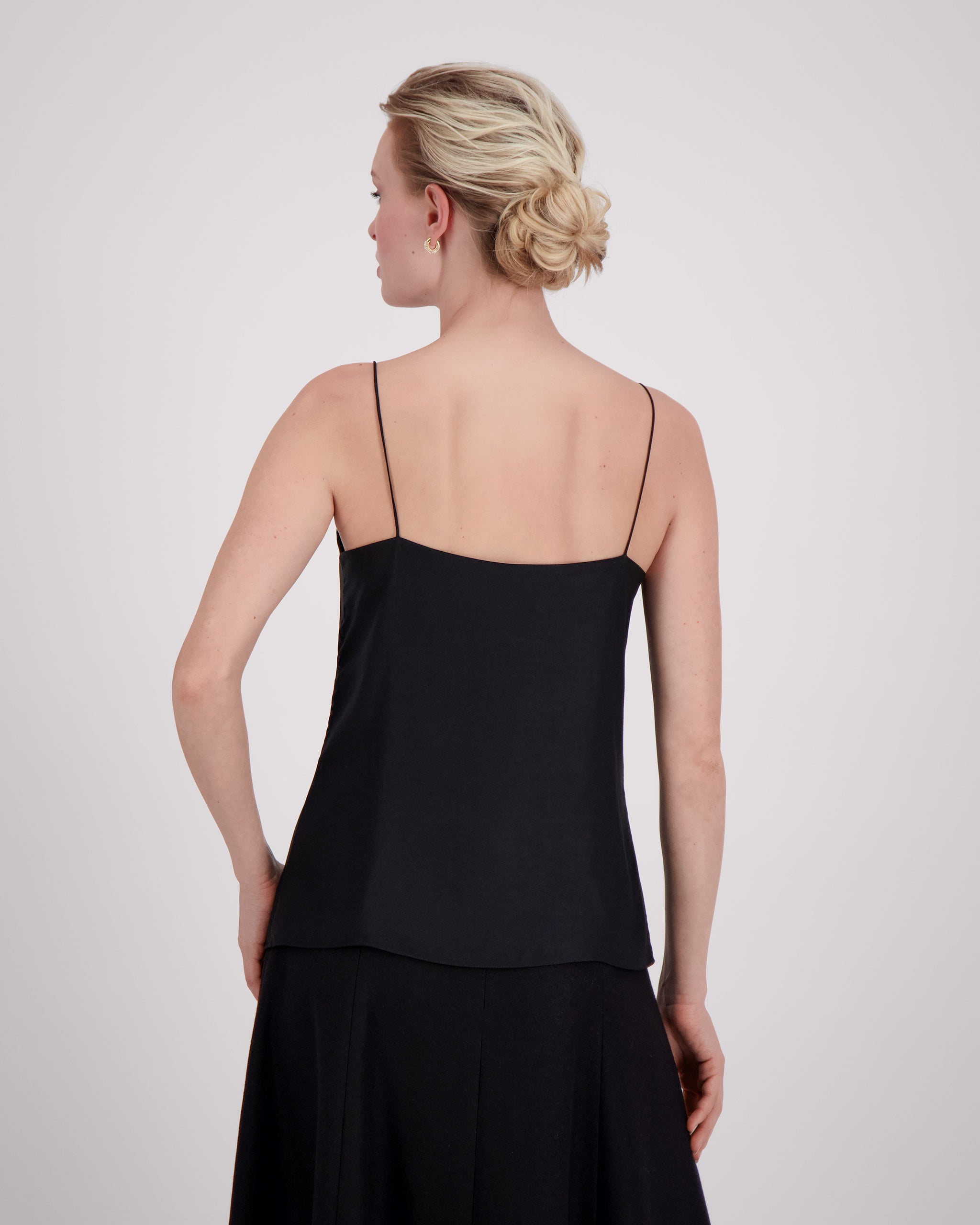 Körpernah geschnittenes Top mit feinen, runden Trägern und dezentem V-Ausschnitt für eine klare, feminine Linie. Unsichtbare Nähte im Ausschnitt bewahren die elegante Reinheit der Silhouette. Sanfte Abnäher und ein doppelt umgeschlagener Saum mit feiner Steppung auf Hüfthöhe setzen edle Akzente. Vollständig gefüttert für höchsten Tragekomfort.