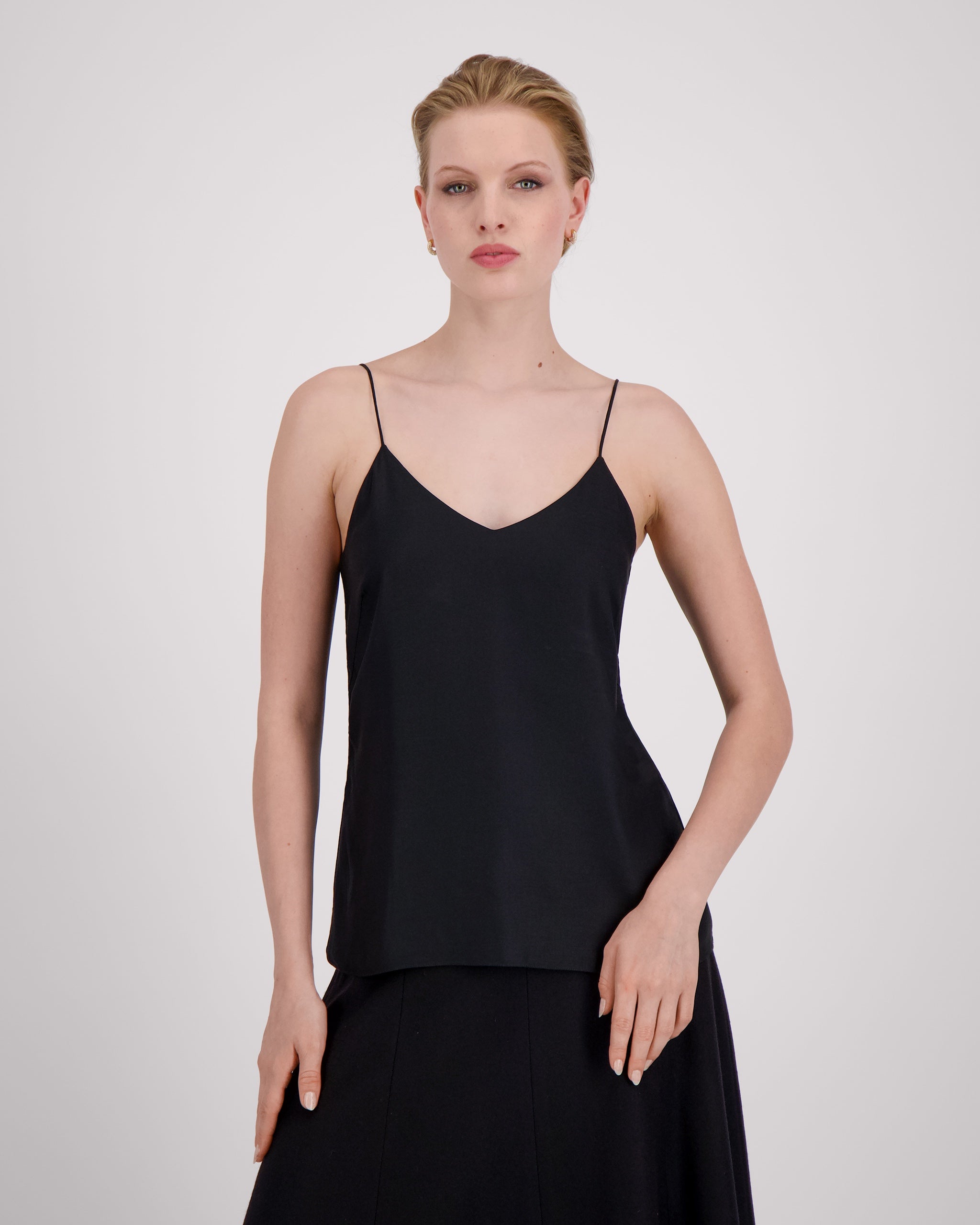 Körpernah geschnittenes Top mit feinen, runden Trägern und dezentem V-Ausschnitt für eine klare, feminine Linie. Unsichtbare Nähte im Ausschnitt bewahren die elegante Reinheit der Silhouette. Sanfte Abnäher und ein doppelt umgeschlagener Saum mit feiner Steppung auf Hüfthöhe setzen edle Akzente. Vollständig gefüttert für höchsten Tragekomfort.