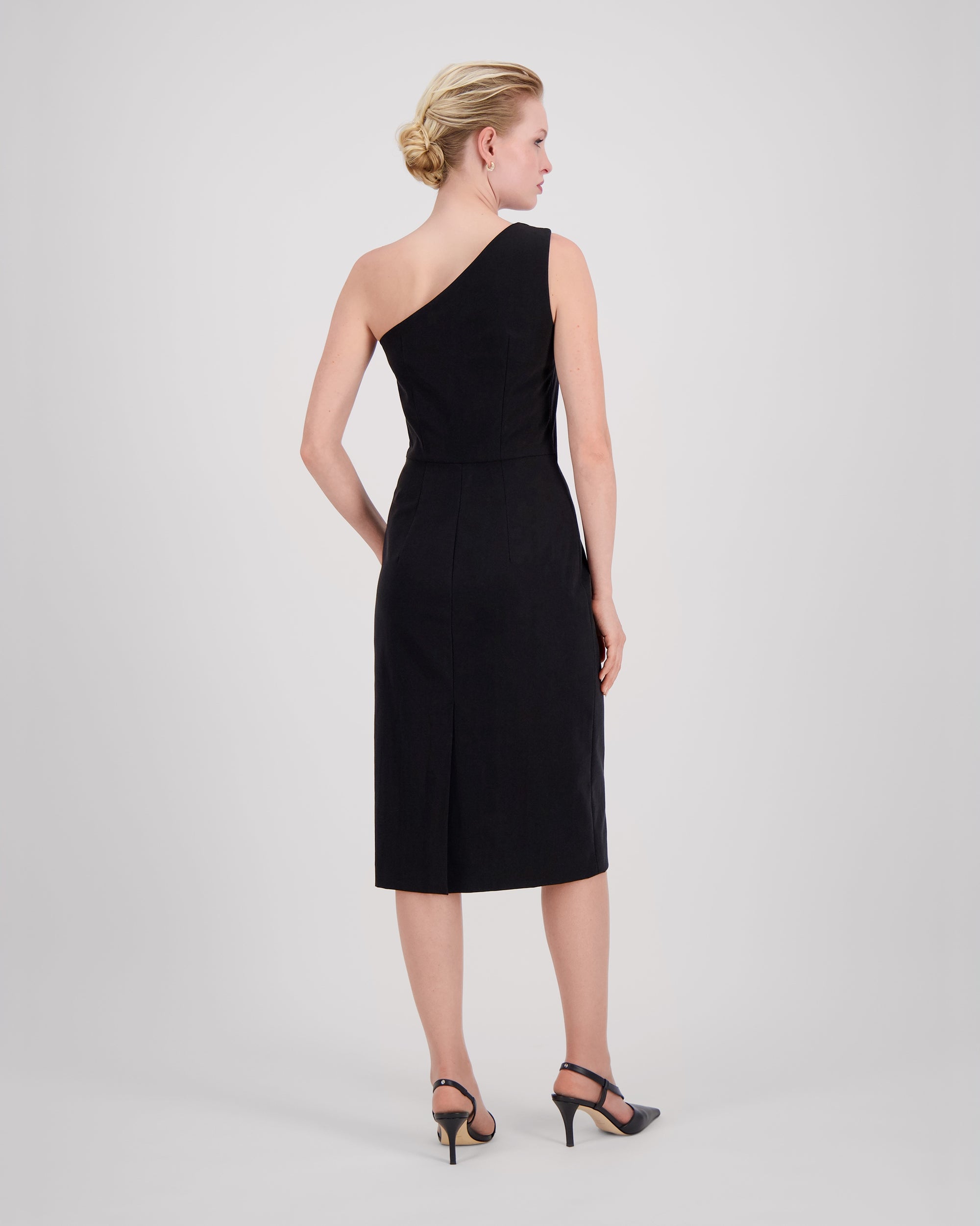 Asymmetrisches Kleid mit skulpturaler Schulterlinie und drei feinen Falten für eine fliessende Drapierung. Figurformende Abnäher vorn und hinten betonen eine elegante Silhouette. Unter dem Knie endend, mit rückwärtigem Gehschlitz für Bewegungsfreiheit. Nahtverdeckter Reissverschluss an der Seite und Blindsaum für ein puristisches Finish.