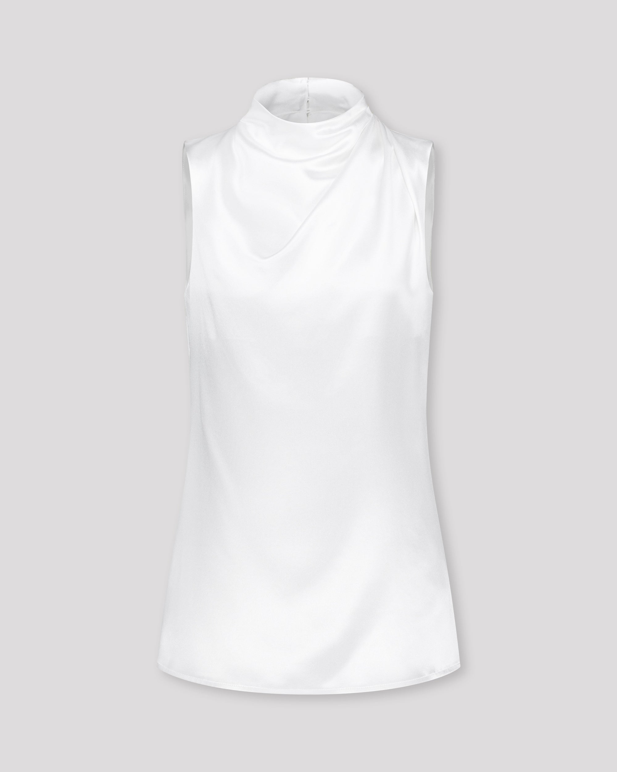 Asymmetrisch geschnittenes Top mit sanft drapierter Schulter für eine feminine, schwungvolle Silhouette. Der hochgeschlossene Stehkragen wird im Rückenteil durch einen feinen Schlitz und drei goldene Knöpfe mit filigranen Knopfschlingen akzentuiert. Ein edles Detail, das das puristische Design um eine subtile Note von Noblesse ergänzt.