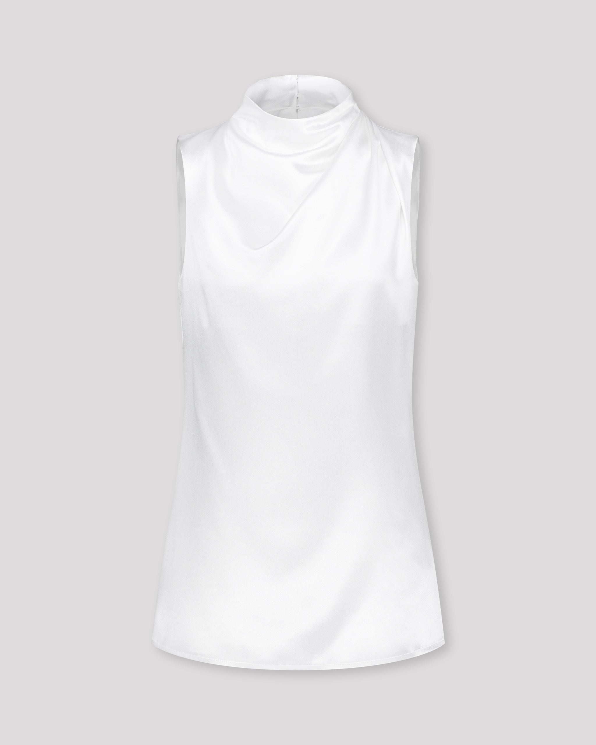 Asymmetrisch geschnittenes Top mit sanft drapierter Schulter für eine feminine, schwungvolle Silhouette. Der hochgeschlossene Stehkragen wird im Rückenteil durch einen feinen Schlitz und drei goldene Knöpfe mit filigranen Knopfschlingen akzentuiert. Ein edles Detail, das das puristische Design um eine subtile Note von Noblesse ergänzt.