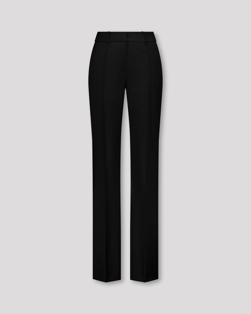 Elegante Hose aus schwarzer Merinowolle mit schmaler Passform und fliessendem Fall. Charakteristische Mittelnaht vorn, dezente Bügelfalte hinten. Verdeckter Bundverschluss mit Corozo-Knopf für eine glatte Frontpartie. Seitliche Eingrifftaschen, rückwärtige Pattentaschen und feine Abnäher formen eine feminine Silhouette mit klarer Linienführung.