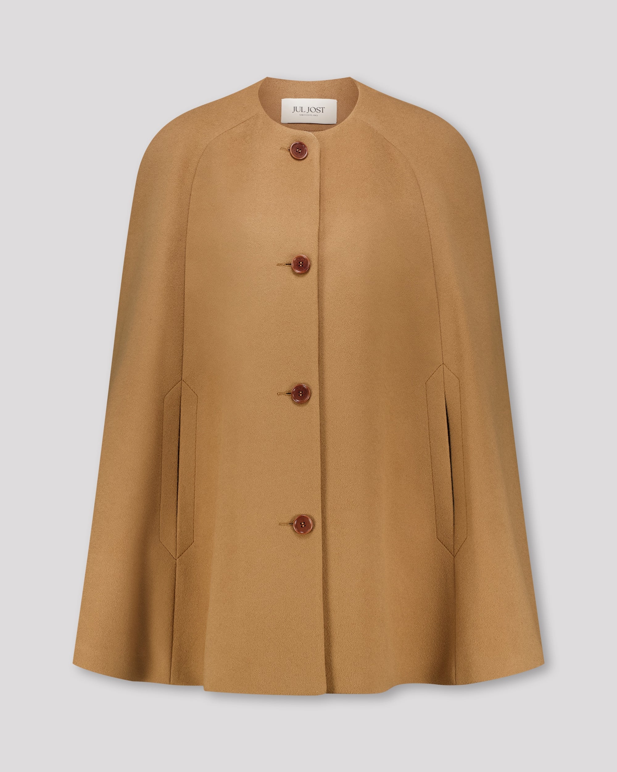 Cape-Mantel aus reinem Kaschmir mit sanft modellierenden Schulterabnähern und fein gearbeiteten Ärmelschlitzen mit zarter Absteppung. Der matte Vier-Knopf-Verschluss aus Corozo hält die Silhouette klar und puristisch. Dezente Eingriffschlitze und eine versteckte Innentasche verbinden Funktionalität mit eleganter, reduzierter Formensprache.