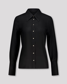 Elegante Bluse mit leicht vergrössertem Kragen und feiner Kantensteppung für ein markantes, selbstbewusstes Statement. Locker fallende Silhouette mit nach vorne versetzter Schulternaht und Rückenfalte für strukturierten, fliessenden Sitz. Durchgehende Knopfleiste mit Corozo-Knöpfen und extralangen Manschetten für präzise, detailreiche Verarbeitung.