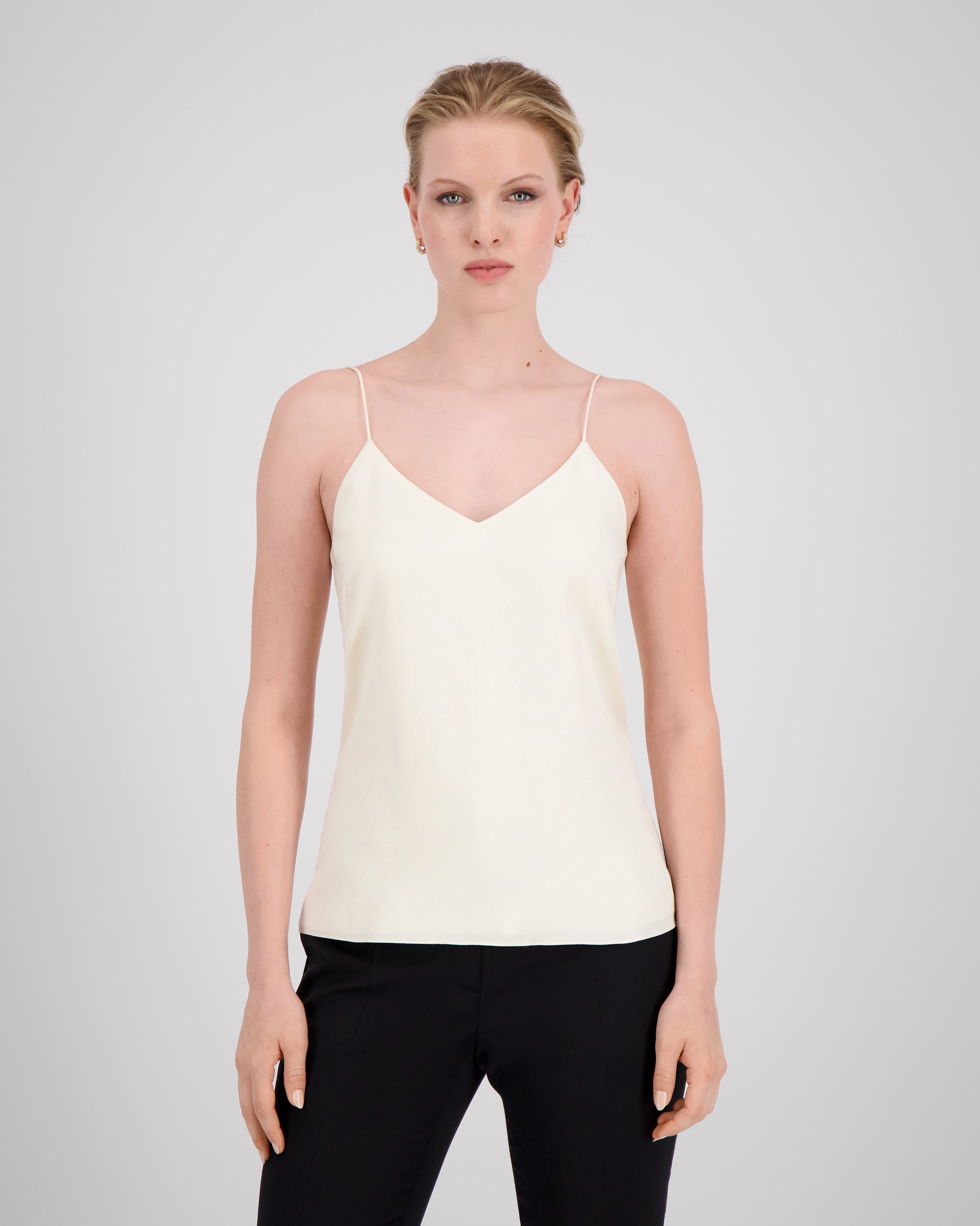 Zartes Top mit feinen, runden Trägern und dezentem V-Ausschnitt für eine klare, feminine Linie. Unsichtbare Nähte im Ausschnitt und sanfte Abnäher betonen die Silhouette mit eleganter Zurückhaltung. Der doppelt umgeschlagene Saum auf Hüfthöhe setzt einen feinen Akzent. Vollständig gefüttert für höchsten Tragekomfort und luxuriöses Finish.